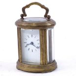 A small oval brass-cased carriage clock, with curved bevelled glass panels, case height 8cm, not