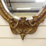 An oval gilt-framed bevelled-edge wall mirror, with 3-branch candle attachment, overall height 85cm