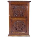 A small Victorian panelled oak cupboard, the relief carved panelled door with armorial crests of