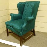 A George III mahogany-framed upholstered wing armchair, with chamfered square legs, upholstered in