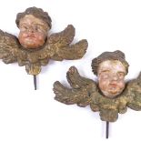 A pair of Italian relief carved painted and gilded wood cherub ornaments, with original metal