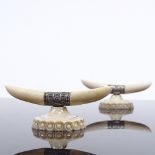 A pair of ivory and silver knife rests, in the form of horns and carved base, width 7cm. Some