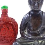 A Chinese patinated spelter seated Buddha, height 10cm, a carved cinnabar snuff bottle, and a carved