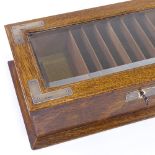 An Edwardian oak and silver-mounted desktop cigar box, with bevelled glass panelled lid and