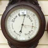 A carved oak-cased aneroid wall barometer and thermometer, ceramic dials, height 87cm