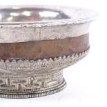 A Tibetan silver-clad and hardwood bowl, with allover chased and embossed decoration