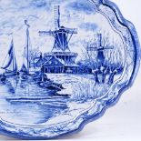 A Delft blue and white pottery wall plaque, with painted canal scene, 39cm across Faint hairline