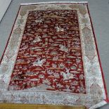 A finely woven Middle Eastern red ground silk rug, depicting hunting scenes