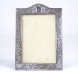 An early 20th century Eastern unmarked silver-fronted rectangular strut photo frame, relief embossed