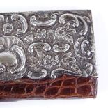 An Edwardian silver-mounted crocodile bi-fold lady's wallet, with relief embossed foliate and floral