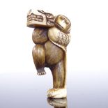 A 19th century Japanese ivory netsuke, monkey carrying a dragon mask, signed, height 5cm
