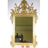 An ornate carved and gilded wood-framed wall mirror in Louis XVI style, with carved and pierced