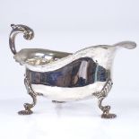 A George V silver sauce boat, shell feet with scrolled C acanthus leaf handle and scalloped rim,