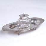 An Edwardian oval silver desk stand, with fitted silver-mounted cut-glass inkwell, by Sydney & Co,