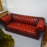 A red studded leather-upholstered Chesterfield settee, with rollover arms, L200cm