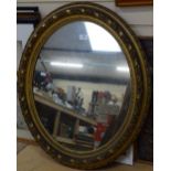 An ornate gilt-framed oval wall mirror, overall height 75cm
