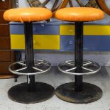 A pair of cast-iron and chrome pub stools with orange seats