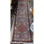 A red ground Turkemon runner with symmetrical pattern, 295cm x 80cm