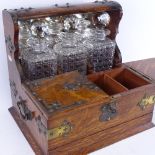 A Victorian oak tantalus with electroplate mounts, containing 3 square cut-glass decanters, all