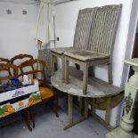 A weathered teak drop leaf garden table, together with 3 matching chairs, and a parasol