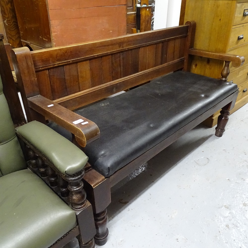 A stained hardwood and upholstered pub bench