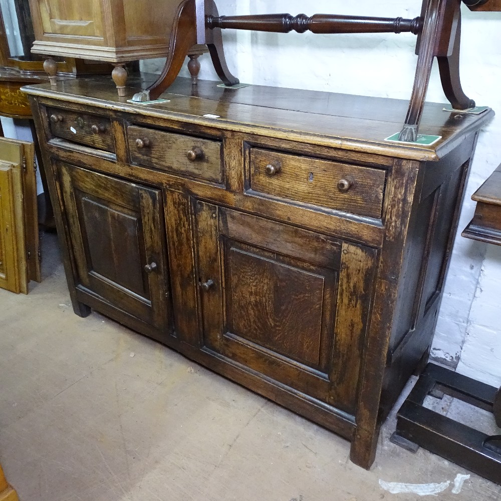 An Antique joined oak dresser base, with frieze drawers and fielded panelled cupboards, on stile
