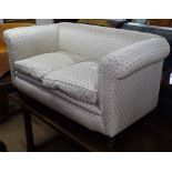 A small Victorian upholstered settee with rollover arms, on turned mahogany legs, L150cm, H75cm,
