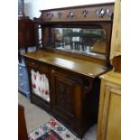 A stylised Arts and Crafts oak sideboard with a raised pierced mirror back, fitted with drawer and