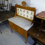 An Edwardian satin-walnut washstand, with marble top, the raised tiled back depicting scenes from