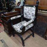 An ebonised upholstered armchair with lion mounts, on X-shaped stretcher