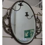 A 19th century brass-framed oval bevel-edge wall mirror, with swivel candlestick fittings, overall