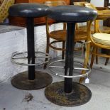 A pair of cast-iron and chrome pub stools with black leather seats