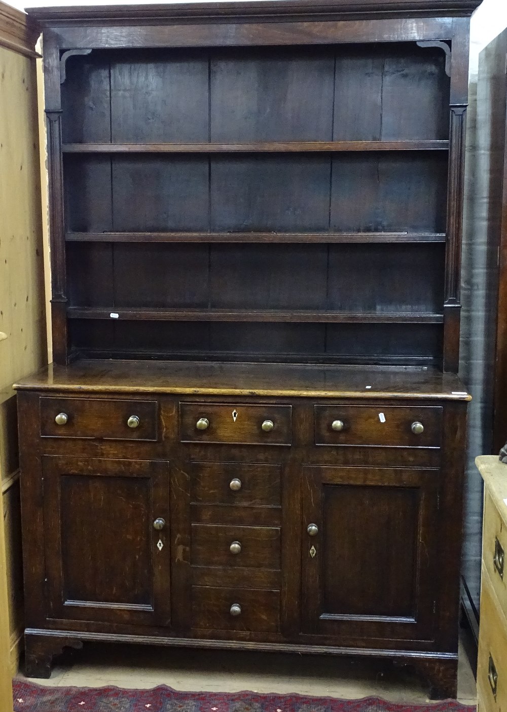 An Antique oak 2-section dresser, having a boarded open plate rack above 3 frieze drawers, with