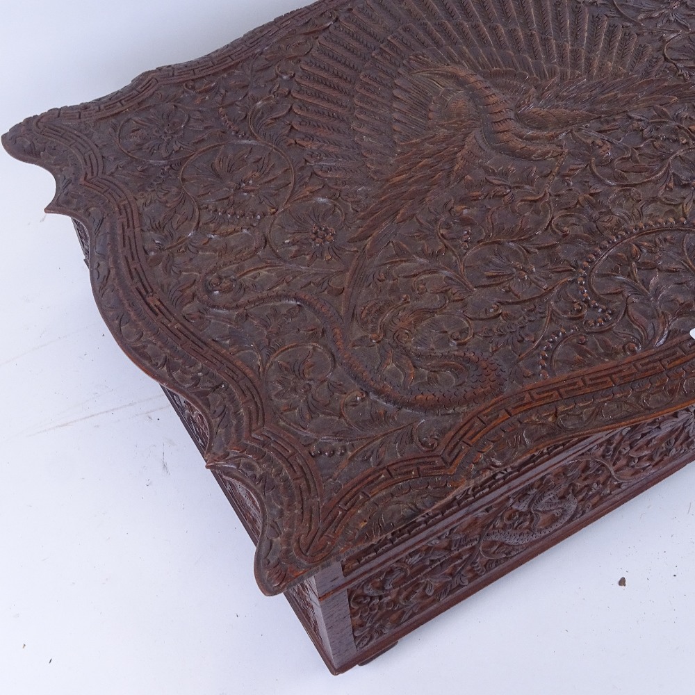A large Indian heavily carved sandalwood work box, peacock and floral decoration, with removeable