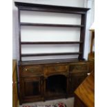 An Antique oak dresser with open plate rack, base fitted with drawers and fielded panelled