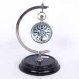 A reproduction nickel and glass-cased ball clock on stand