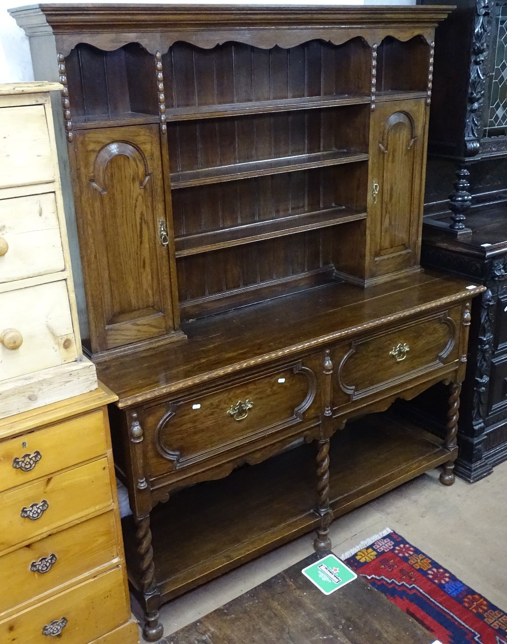 An oak 2-section dresser, the top fitted with fielded panelled cupboards and open shelves, 2