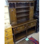 An oak 2-section dresser, the top fitted with fielded panelled cupboards and open shelves, 2