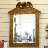 A modern gilt-framed bevelled-edge wall mirror, floral decorated frame surmounted by an eagle,
