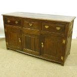 An 18th century panelled oak dresser base, with 3 frieze drawers and panelled cupboards under,
