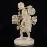 A Japanese ivory okimono of a basket seller, Meiji Period, with inset signed jade plaque under base,