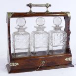 A Victorian oak 3-bottle tantalus, with electroplate mounts and square cut-glass decanters, length