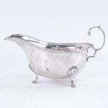 A George VI silver sauce boat, with engraved rim on 3 shell feet with scrolled acanthus leaf C-