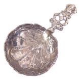 A German silver caddy spoon, Hanau, pierced figural and floral handle with shell pattern bowl,