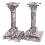 A pair of silver plated Corinthian column squat table candlesticks, relief embossed decoration, with