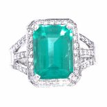 A rectangular emerald and diamond cluster ring, central large emerald step-cut emerald approx 3.