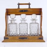 A Victorian oak 3-bottle tantalus, with electroplate mounts and glass decanters, length 32cm (A/F)