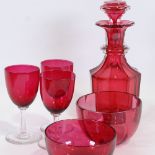 A cranberry glass decanter, two cranberry glass finger bowls and three glasses, decanter height