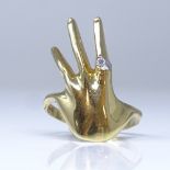 An 18ct gold figural hand ring, index finger set with a round brilliant cut diamond, diamond