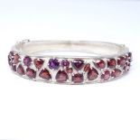 A modern sterling silver vari-cut garnet cluster hinged bangle, set with round, pear, oval,